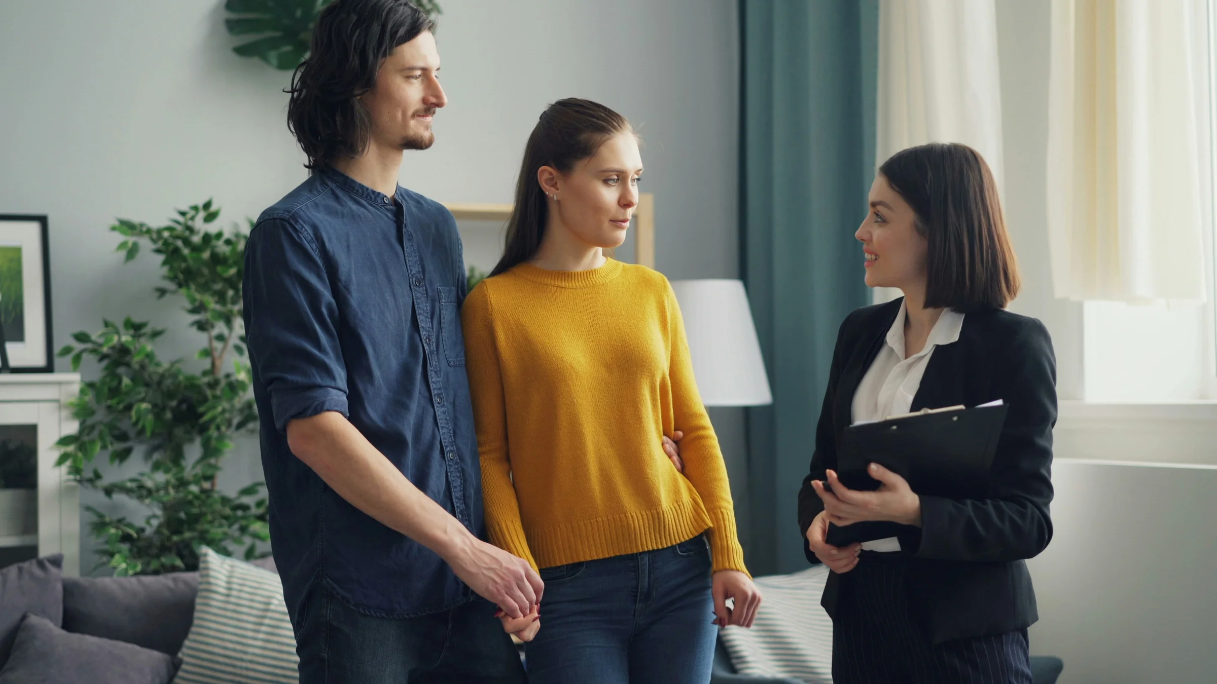 Young couple discussing home plans with a professional who holds a clipboard